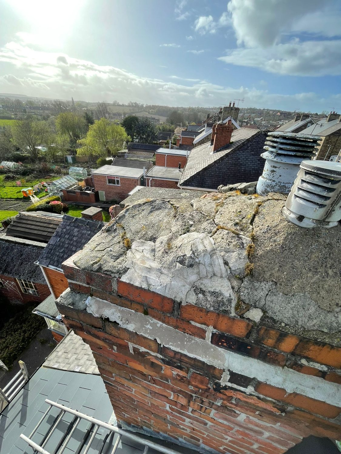 Badly weathered chimney stack with cracked and eroded brickwork before repair
