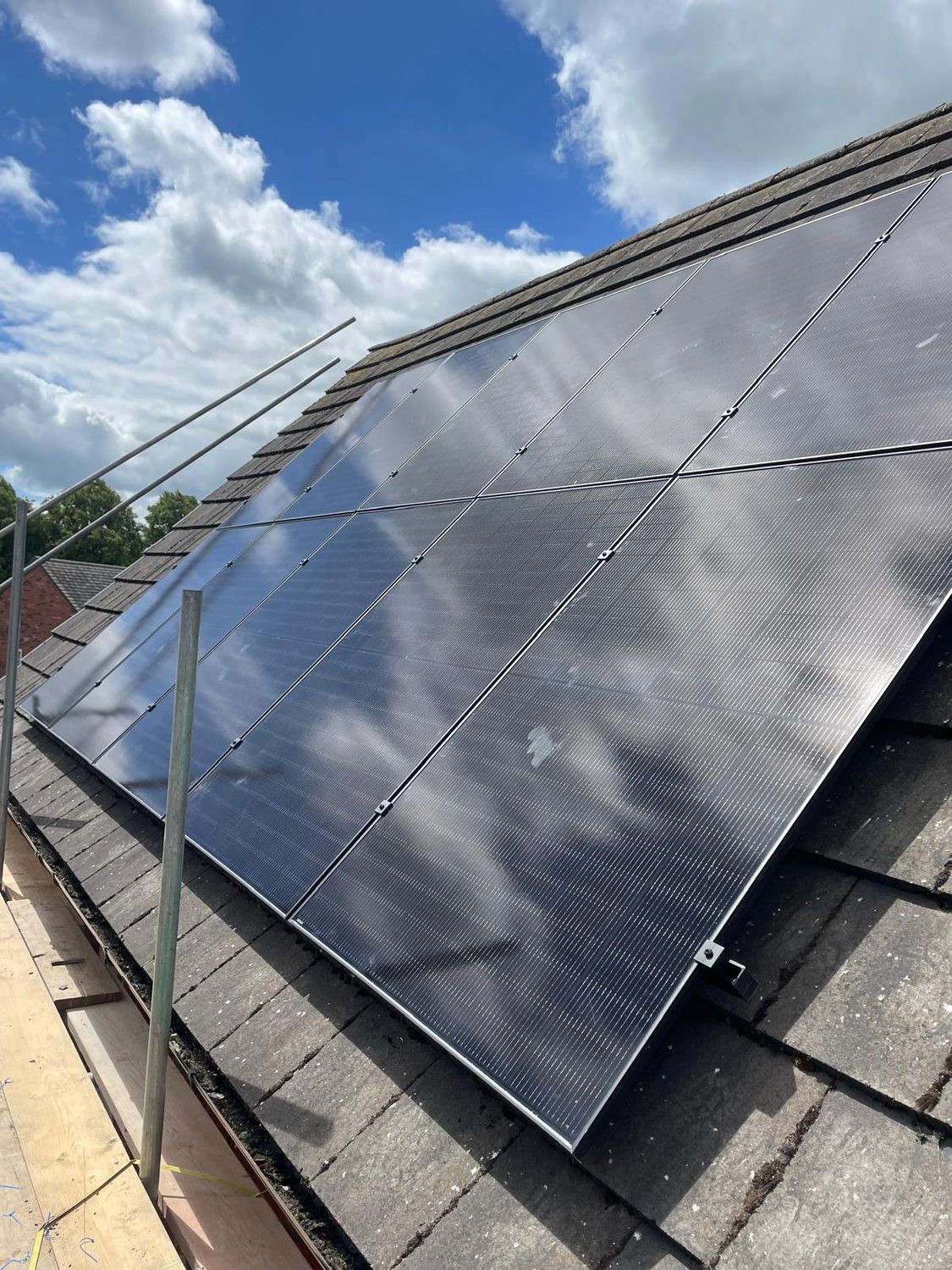Black solar panels installed across a tiled roof under a blue sky