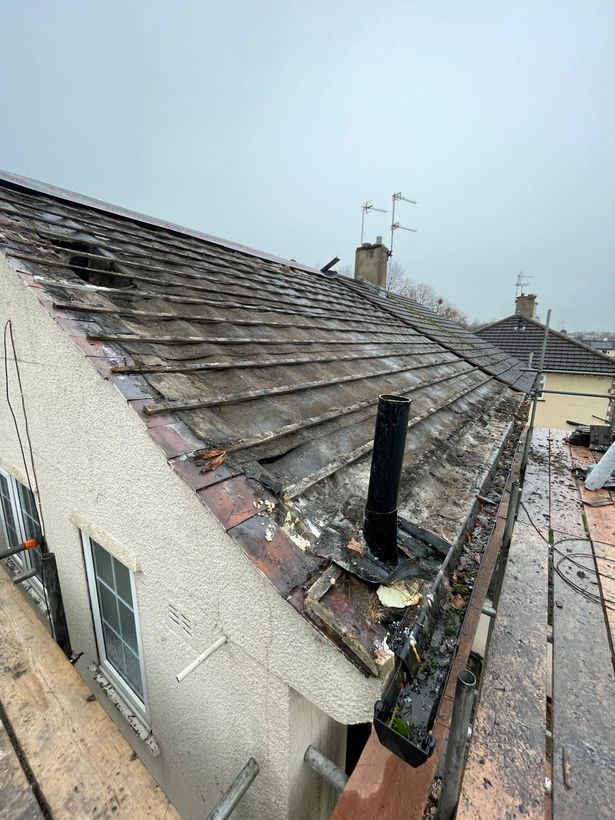 Roof before the work: old cracked tiles, exposed battens, failed flashing around the flue and a wet grey day