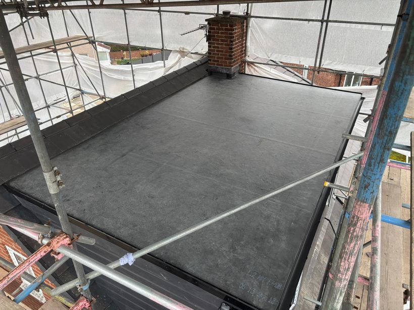 Finished rubber dormer roof with the chimney flashed in
